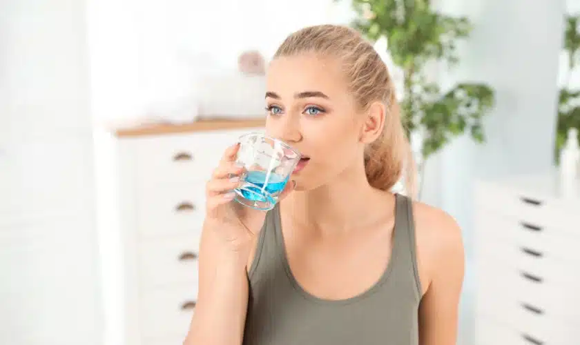 A lady is washing her mouth with alcohol based mouth wash